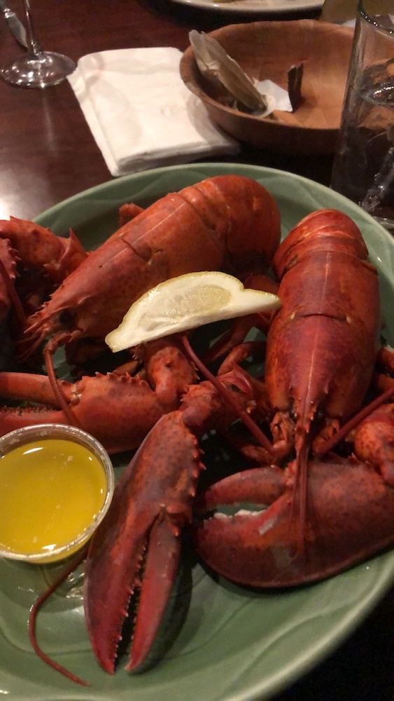 A photograph of two boiled lobsters on a plate.