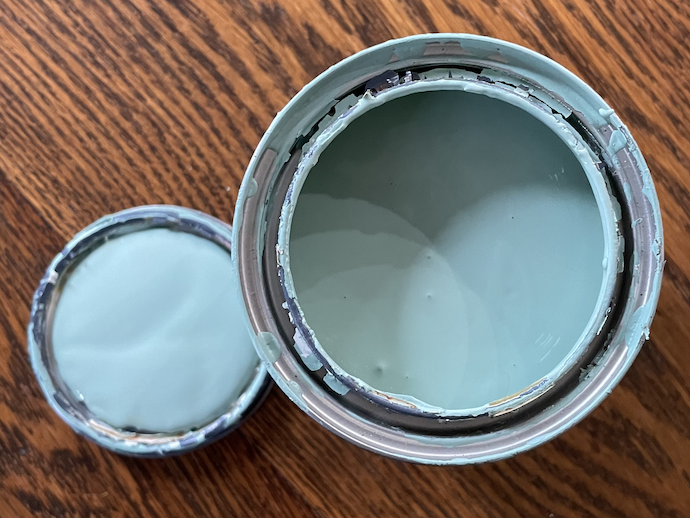 一张蓝色油漆罐的照片，它的盖子放在桌子上。