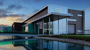 The MTC factory at sunset with a pond in the foreground.