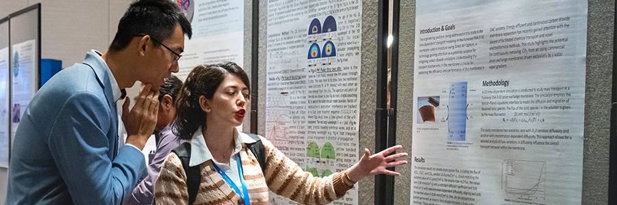 Two COMSOL Conference attendees discussing a poster in the poster hall.