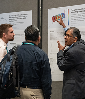 A conference attendee presenting their poster to two other individuals.