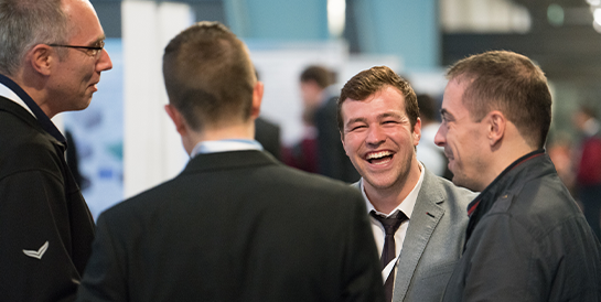 Four COMSOL Conference attendees having a conversation in the poster hall.