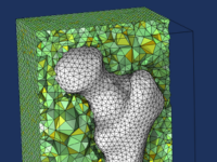 A close-up of a simulation mesh of a femur and a surrounding block.