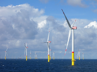 Un cluster de turbines dans un parc éolien offshore en pleine mer et sous un ciel nuageux.