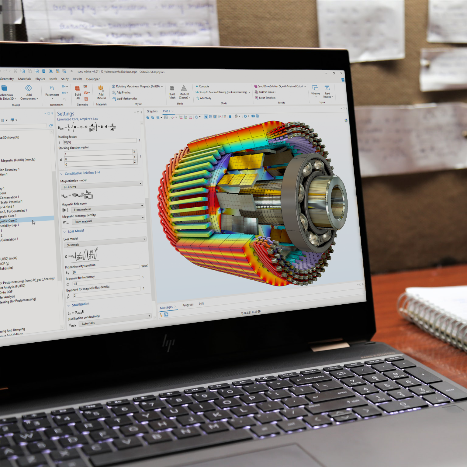 A laptop computer showing the COMSOL Multiphysics UI with an electric motor model in the Graphics window.