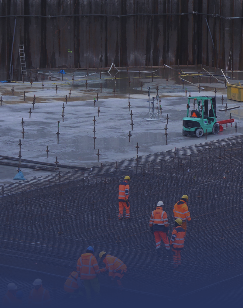 A wide shot of a construction site in the Netherlands, where construction workers are preparing the area for concrete.