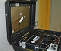 A motorcycle top case is open with antennas and wires inside.