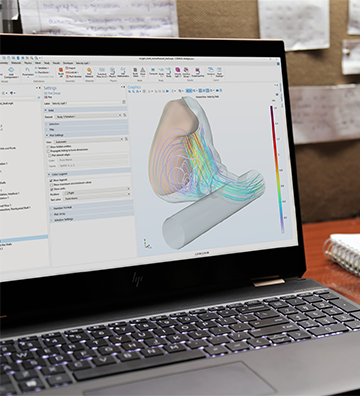 A computer running the COMSOL Multiphysics software with an oxygen mask model in the Graphics window.