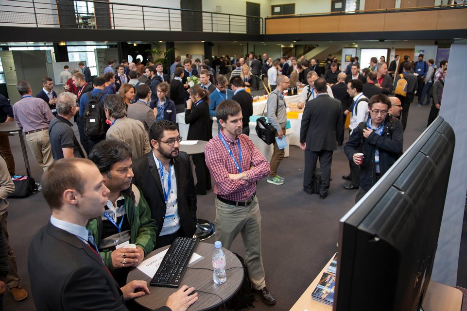 A photograph of conference attendees learning about COMSOL Multiphysics at a demo station.