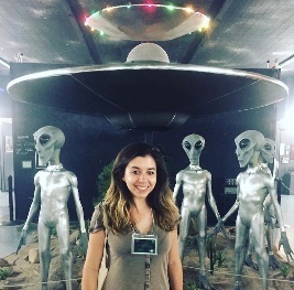 A photograph of a person standing in front of a UFO exhibit in Roswell.