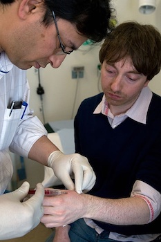 A photo of a surgeon implanting an RFID microchip into someone's hand.