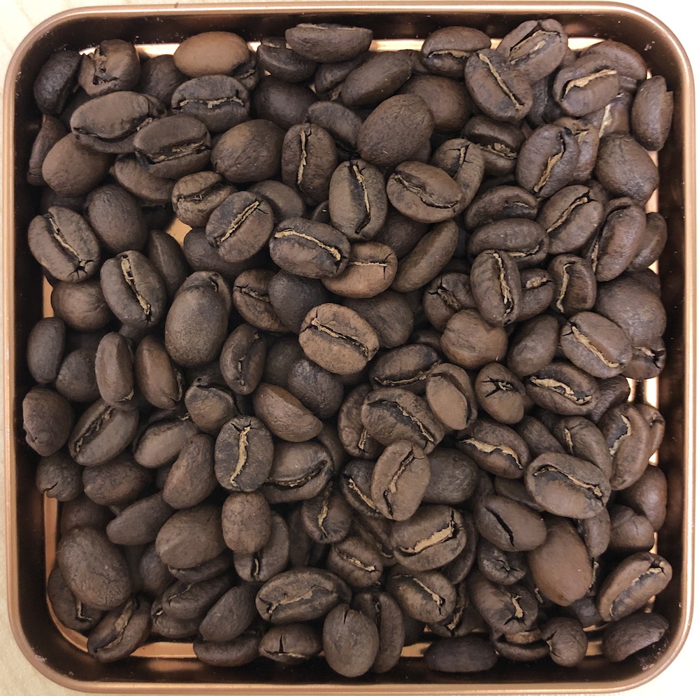 A photograph of coffee beans in a tin.