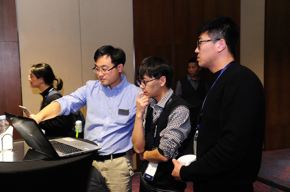 A photograph of attendees discussing modeling problems with a COMSOL application engineer.