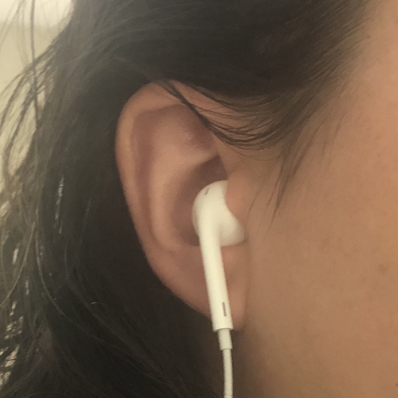 A photograph of a person wearing an earbud in their ear.