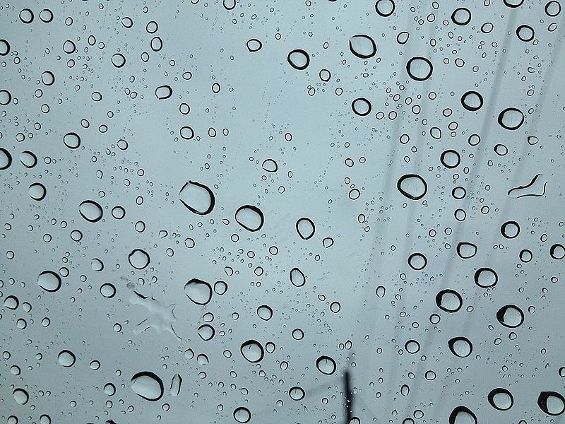 A photograph of water droplets on a glass surface.