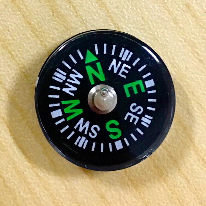 A photograph of a modern compass resting on a wooden table.
