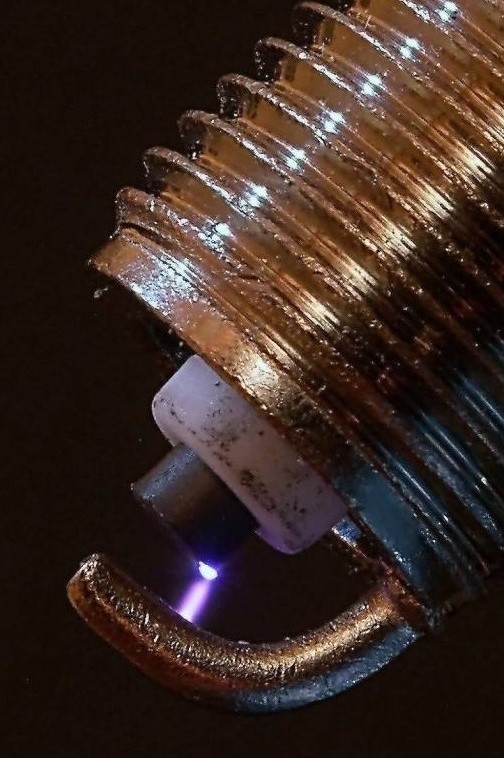 A photograph of an automotive spark ignition against a black background.