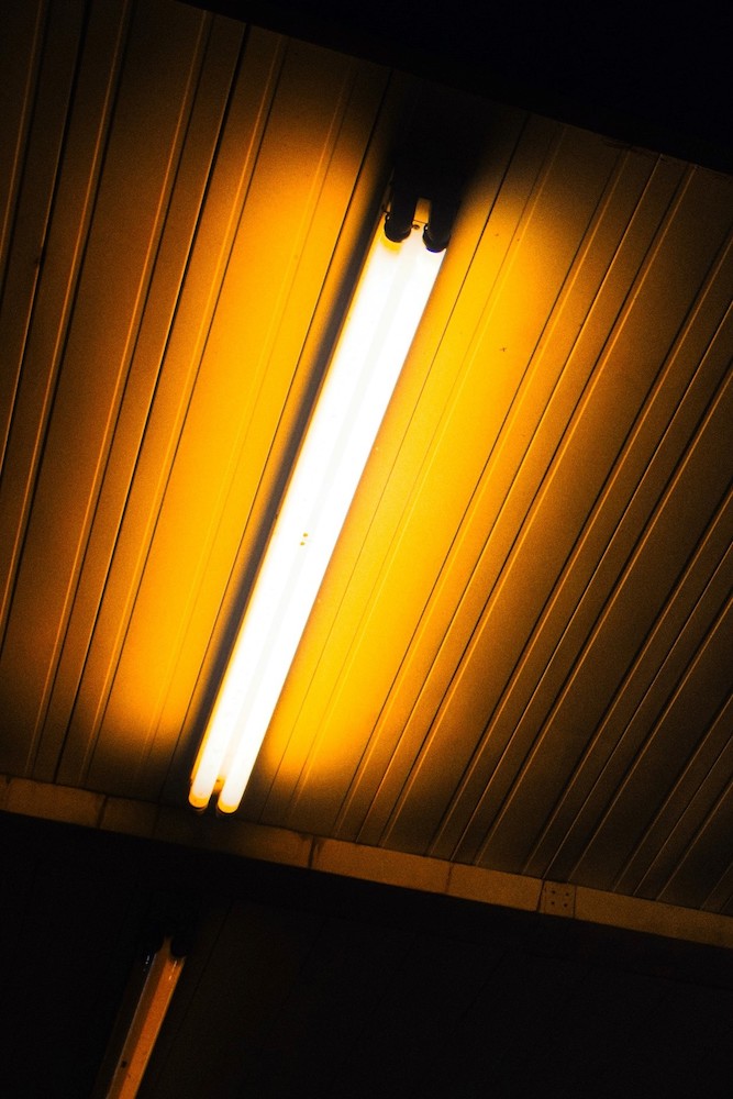 A photograph of a fluorescent bulb on the ceiling of a darkened room.