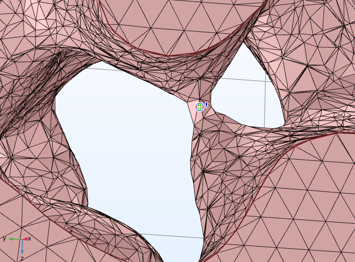 The surface mesh of a porous structure shown in red, with the center of rotation set with a small icon.