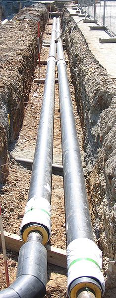 A photograph of two large pipelines placed in a dug out hole.