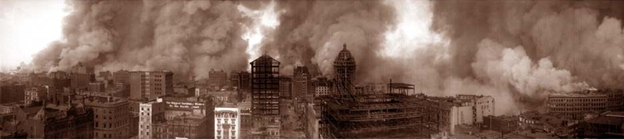 A sepia-toned photo of the San Francisco skyline during the 1906 earthquake, with many buildings smoking and on fire.