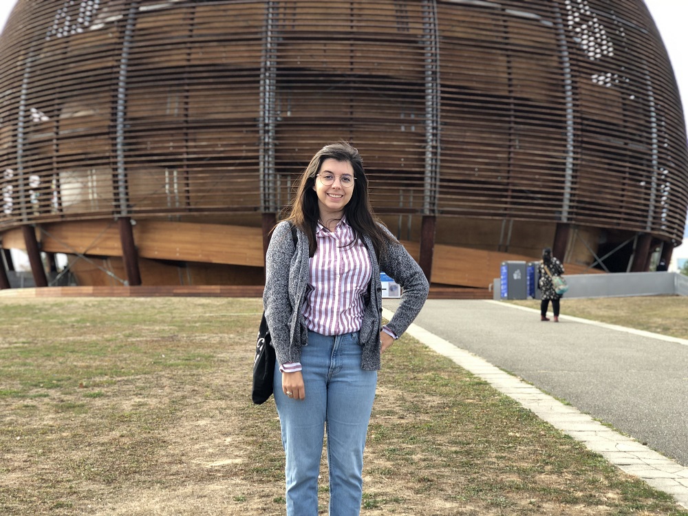 一张女生站在欧洲核子研究中心建筑前的照片。