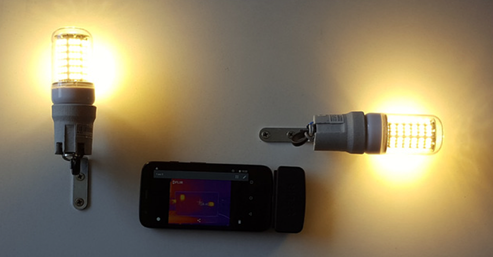 A photograph of the experimental setup for verifying the LED bulb model, with two LED bulbs turned on and an infrared camera in the center.