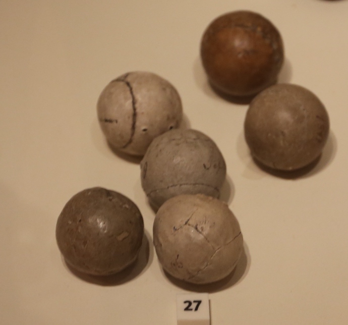A photograph of 6 featherie golf balls on a white surface.