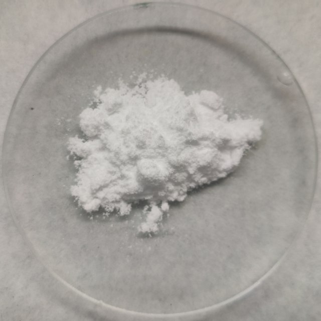 Melamine in white powder form gathered on a clear plate.