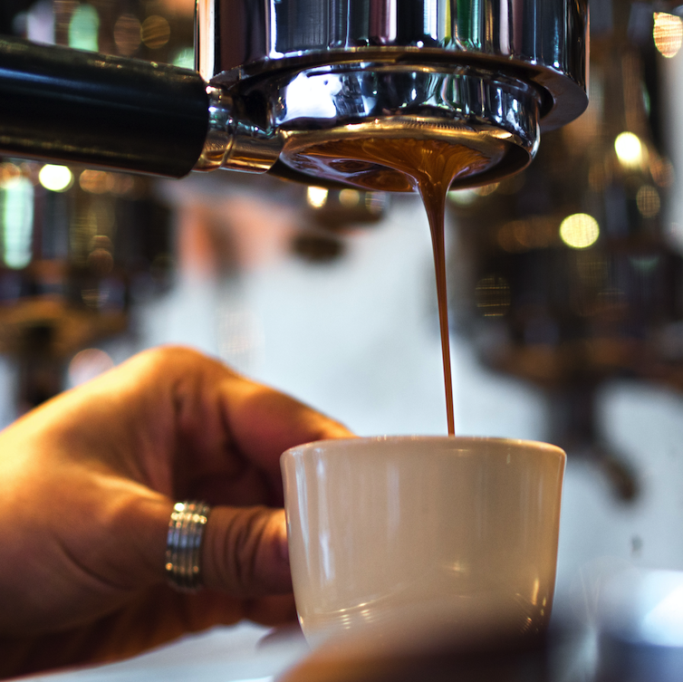 A modern espresso machine making a shot of espresso with a portafilter.