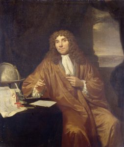 A portrait of Antonie van Leeuwenhoek where he is sitting and writing.