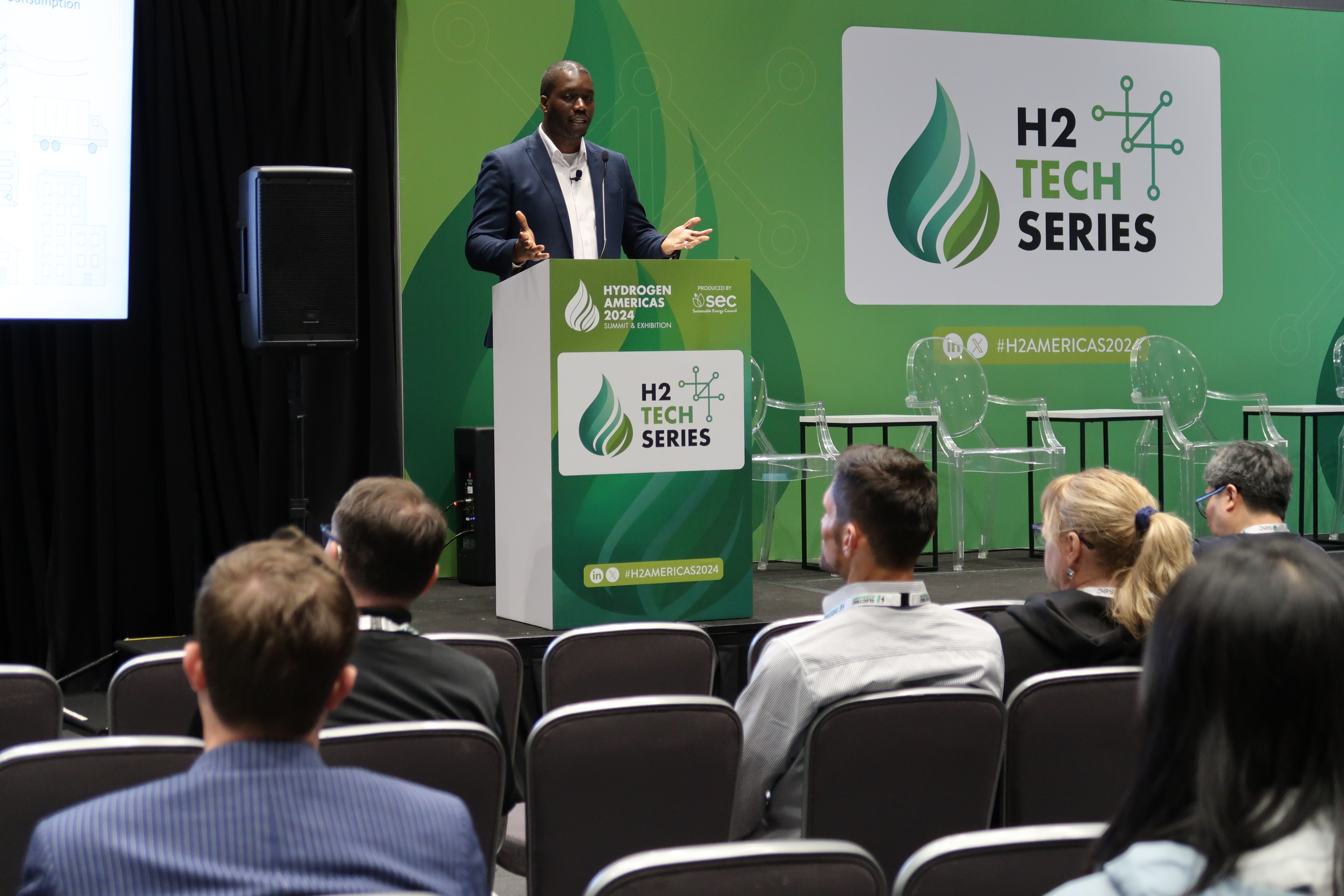 A speaker presenting on the H2 Tech Series stage.