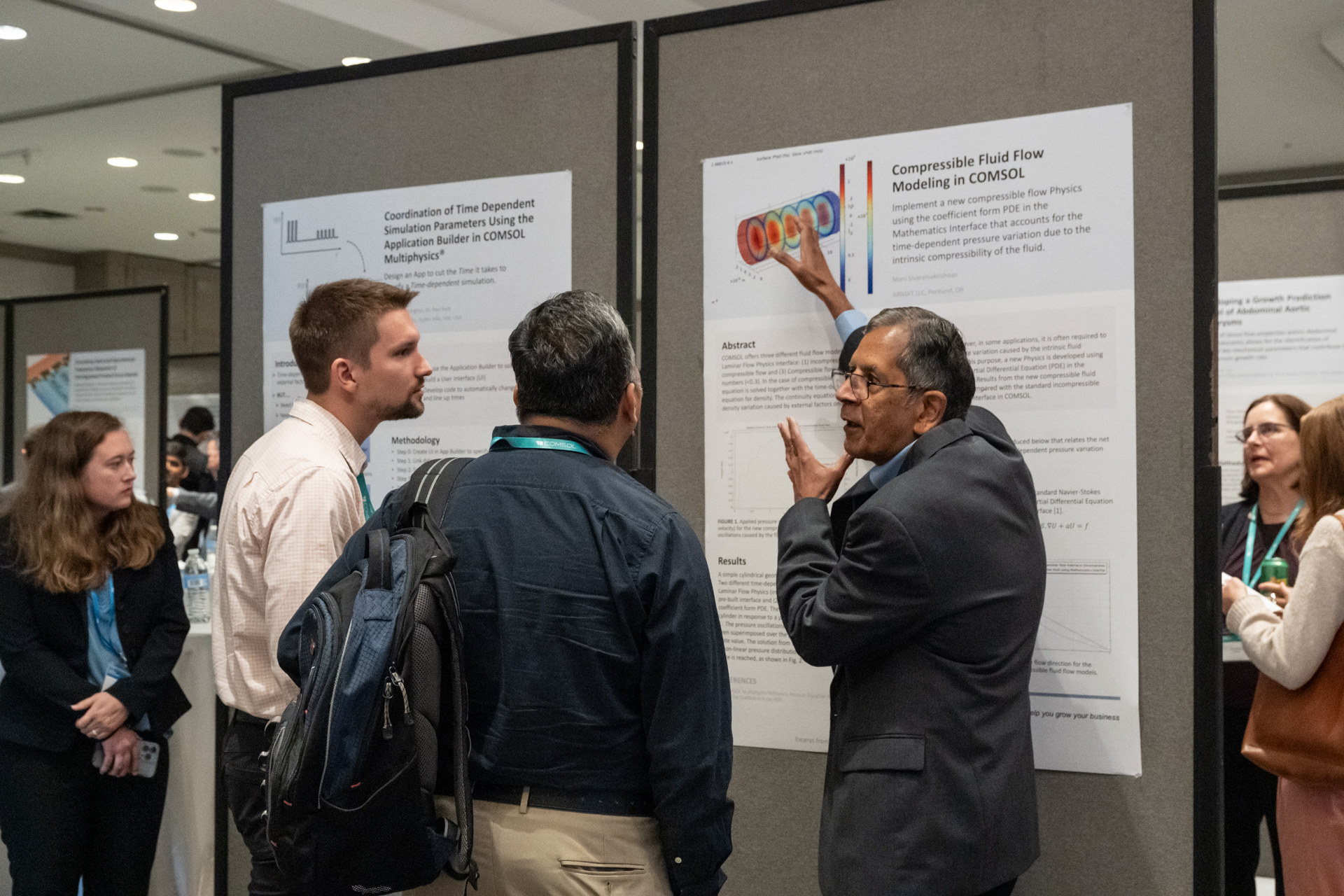 A conference attendee discusses his work with COMSOL engineers. 