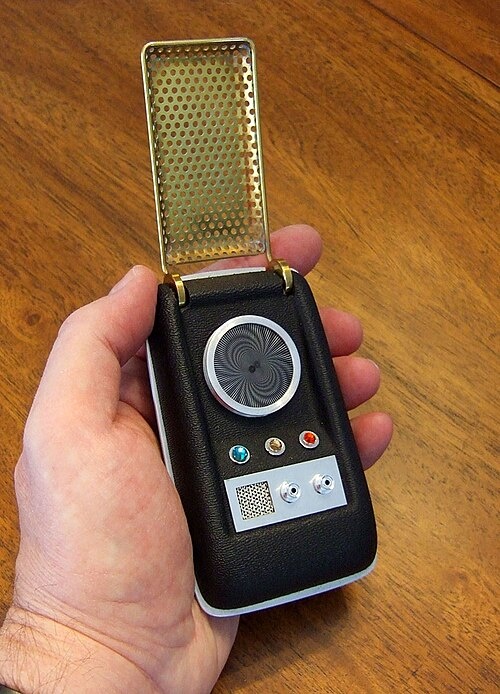 A close-up of a hand holding a reproduction of a Star Trek communicator.